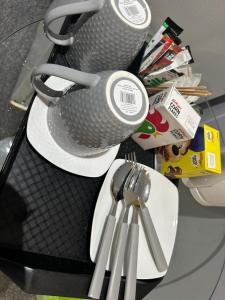 a table with a cup and utensils on a plate at Deluxe Studio Coventry in Parkside