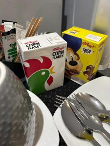 a table with a box of corn flakes cereal and a plate with a spoon at Deluxe Studio Coventry in Parkside