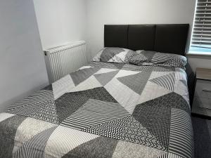 a bedroom with a bed with a black and white comforter at Deluxe Studio Coventry in Parkside