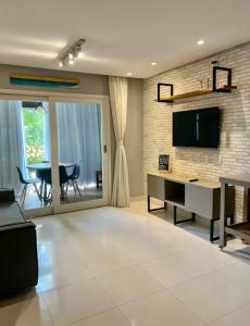 a living room with a television and a table with chairs at Prestes Exclusive - Pipa Ubaia in Pipa