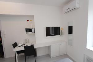 a white kitchen with a table and a tv on a wall at Apartments Simple Teslina in Zagreb