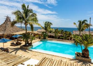 a swimming pool with palm trees and the ocean at Las Cabañas de Antica in Vichayito