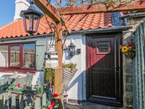 ein Haus mit einer roten Tür und einem Tisch und Stühlen in der Unterkunft The Old Mill Cottage in Whitby