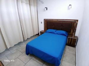 ein Schlafzimmer mit einem blauen Bett in einem Zimmer mit Vorhängen in der Unterkunft casa oasis in Tecomán