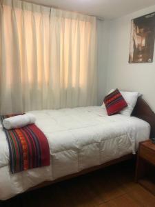 un letto in una camera con finestra e tende bianche di Hotel TIKA AYNA Cerca a la plaza de Armas CUSCO a Cuzco