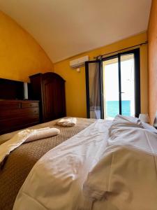 a bedroom with a large bed with a large window at TRAMONTO SUL MARE by CefaLux in Cefalù