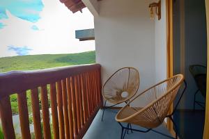 a balcony with two chairs and a large window at Casa dos Pássaros - AR Condicionado nos dois quartos in Lençóis