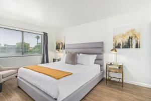 a white bedroom with a bed and a chair at Camelback 446 at Fashion Square in Scottsdale