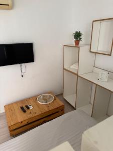 Una sala de estar con una mesa y un televisor en la pared. en Le cocon lumineux, en Sfax