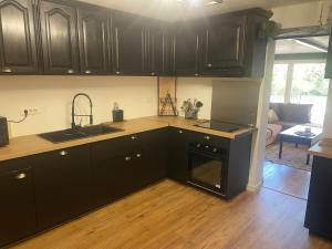 a kitchen with black cabinets and a sink and a stove at Maison de vacances in Caussens