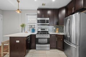 a kitchen with wooden cabinets and a stainless steel refrigerator at NYNJ World Cup 26 Fan Zone Queens Kasa Boho Rentals Sleeps 4 persons in Brooklyn Manor +4 photos