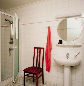 a bathroom with a sink and a mirror and a chair at Blanckthys Hotel Voeren in Voeren