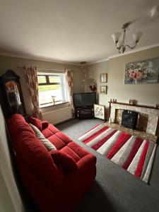 un salon avec un canapé rouge et une cheminée dans l'établissement Laurel Country Cottage, à Ballymena