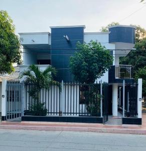 a blue and white house with a gate and trees at Apartamento EURARE in Ríohacha