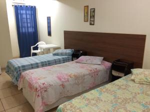 Habitación de hotel con 2 camas y mesa en Comfoort Hotel en Volta Redonda