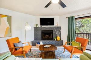 a living room with orange chairs and a fireplace at Mid-Century Flagstaff Mtn Condo in Flagstaff