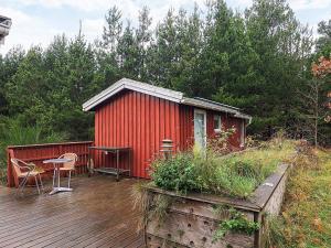 a red cabin with a table and chairs on a deck at 6 person holiday home in Ålbæk-By Traum in Ålbæk