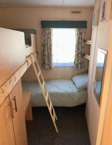 ein kleines Zimmer mit einem Etagenbett und einer Leiter in der Unterkunft Promenade park 8 Berth caravan next to the beach entrance, WIFI included in Ingoldmells