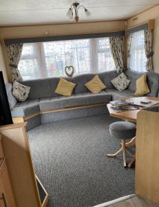 ein Wohnzimmer mit Sofa und Tisch in der Unterkunft Promenade park 8 Berth caravan next to the beach entrance, WIFI included in Ingoldmells