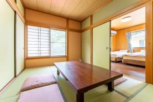 a dining room with a wooden table and a bedroom at Green Oasis Cottage B in Hakone