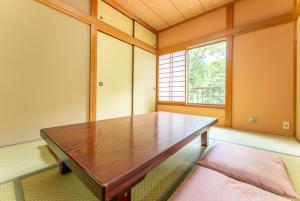 a dining room with a wooden table and a window at Green Oasis Cottage B in Hakone