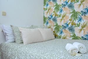 a bed with a pillow and a tropical wallpaper at Live Oporto Rooms in Porto