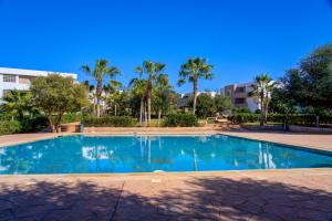 a swimming pool with palm trees and a building at Lunja vibe in Agadir nʼ Aït Sa