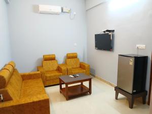 a living room with a couch and chairs and a tv at Veera Residency Gingee in Gingee