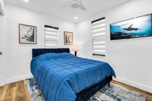 a bedroom with a blue bed in a room with windows at Modern Home with large private yard - Next to downtown & beach & airport - Pet friendly in Fort Lauderdale