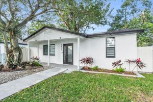 a white house with a green yard at Modern Home with large private yard - Next to downtown & beach & airport - Pet friendly in Fort Lauderdale