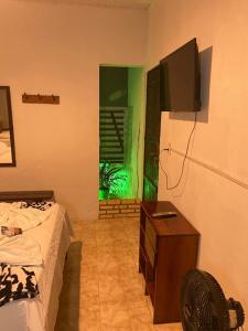 a bedroom with a bed and a tv on the wall at Pousada Cantinho do Dodó in Mulungu