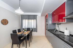 a kitchen with a table with black chairs and red cabinets at Casa da Cortiça in Seixal