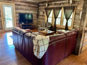 a living room with a leather couch and a television at New Listing- Tecumseh Trail Cabin in Nashville