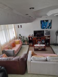 a living room with two couches and a flat screen tv at Martin de Sá - Casa da Olivia in Caraguatatuba