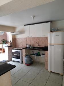 a kitchen with white cabinets and a white refrigerator at Martin de Sá - Casa da Olivia in Caraguatatuba