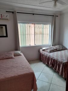 a bedroom with two beds and a large window at Martin de Sá - Casa da Olivia in Caraguatatuba +13 photos