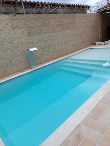 a swimming pool with blue water in front of a brick wall at Martin de Sá - Casa da Olivia in Caraguatatuba