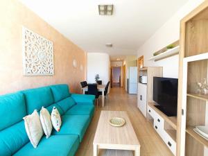 a living room with a blue couch and a tv at Cala Grande suites 3 hab, vistas al mar y terraza in El Cabo de Gata