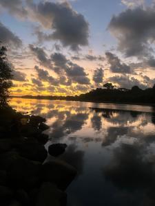 a sunset over a body of water with clouds at Boutique Rooms River Front at La Junta in Dominical