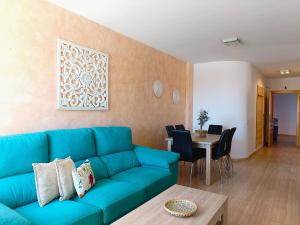 a living room with a blue couch and a table at Cala Grande suites 3 hab, vistas al mar y terraza in El Cabo de Gata