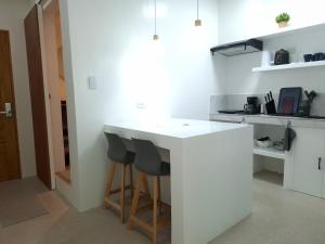 a white kitchen with a white counter and stools at Boracay Luxury Apartments in Boracay