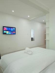 a bedroom with a white bed with a tv on the wall at Boracay Luxury Apartments in Boracay