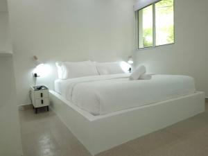a white bedroom with a white bed and a window at Boracay Luxury Apartments in Boracay