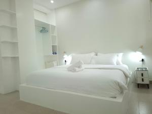a white bedroom with a large white bed with white pillows at Boracay Luxury Apartments in Boracay