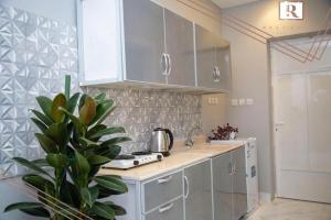 a kitchen with white cabinets and a potted plant at Sukoon alraha serviced apartment in Hafr Al-Batin