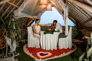 a bride and groom sitting at a table in a wedding cake at Penida Bambu Green Suites in Nusa Penida +36 photos