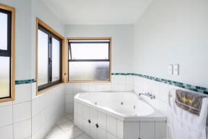 a white bathroom with a tub and windows at Spacious modern executive home in Wellington +35 photos
