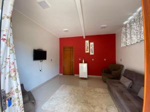 Una sala de estar con un sofá y un televisor. en Suites Flor de Lis, en Pirenópolis