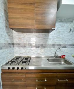 une cuisine avec une cuisinière et un évier dans l'établissement Elegante apartamento a 10 min del aeropuerto El Dorado, à Bogotá