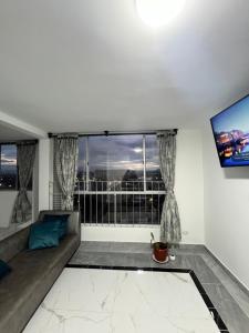 un salon avec un canapé et une grande fenêtre dans l'établissement Elegante apartamento a 10 min del aeropuerto El Dorado, à Bogotá